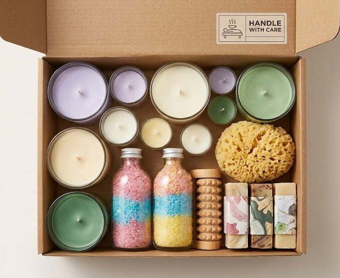 Top-down photo of candles and home scents inside an open box